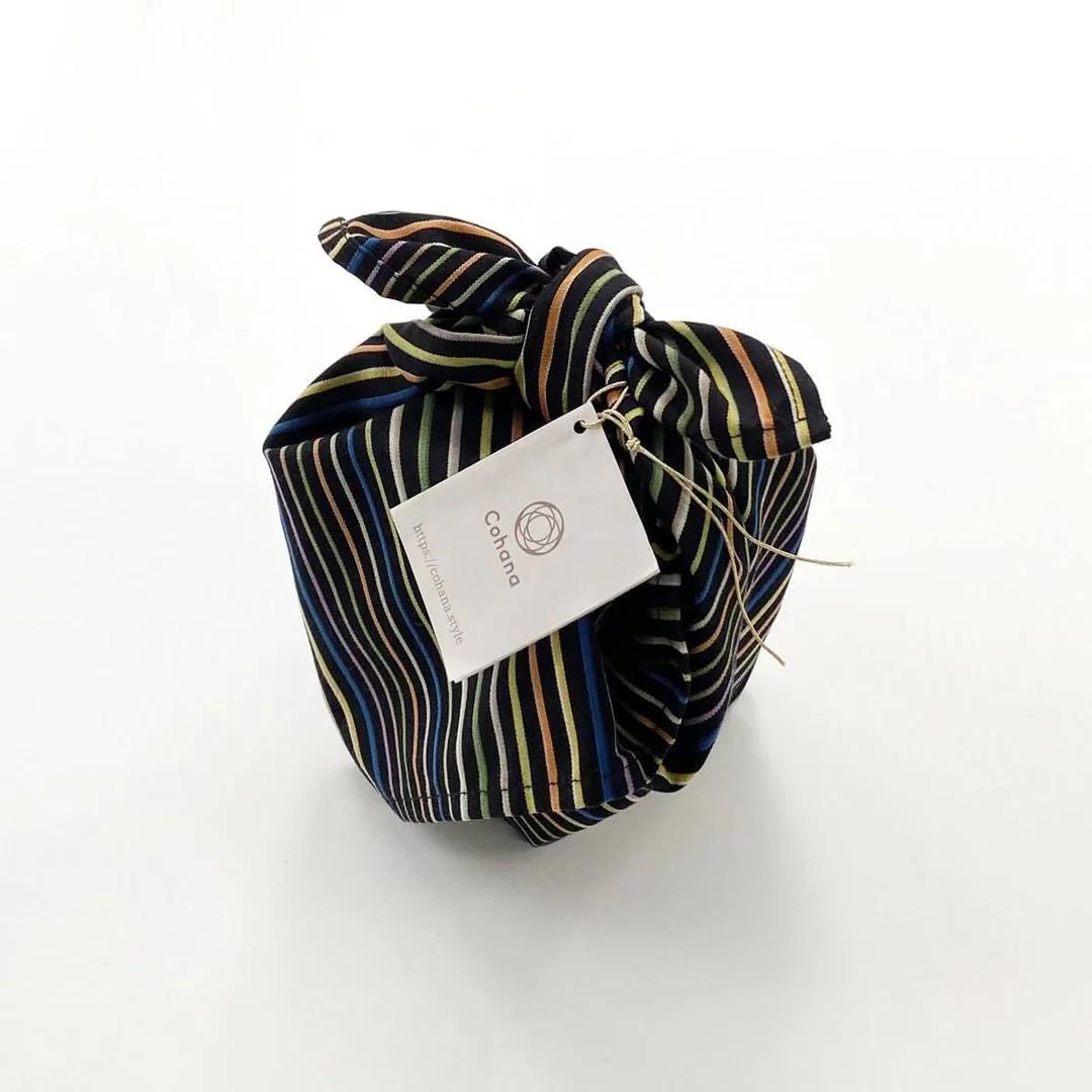 A wrapped gift box with a striped fabric and a white tag attached to it.