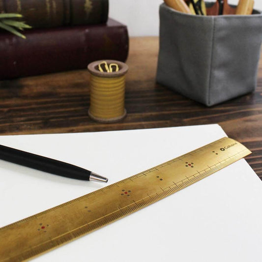 a desk with various office supplies, including a ruler, pen, and a small container holding pens and pencils.