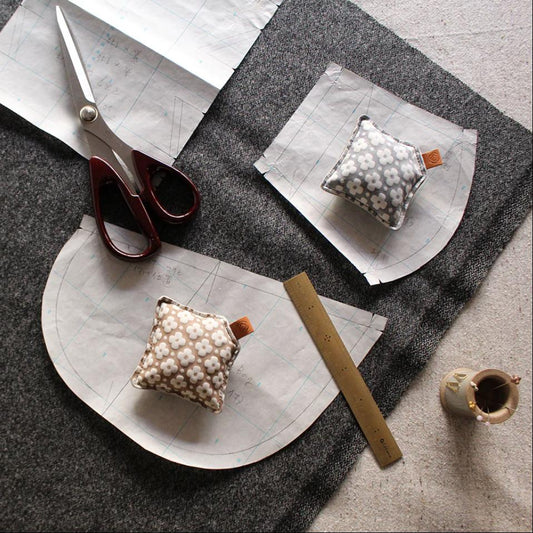 a sewing or crafting workspace with various tools and materials, including a pair of scissors, a ruler, and a small fabric item.