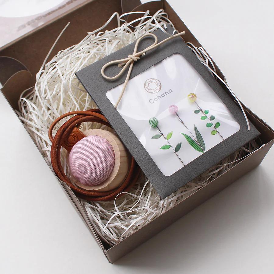 A gift box containing a pink ball, a brown cord, and a framed picture of flowers.