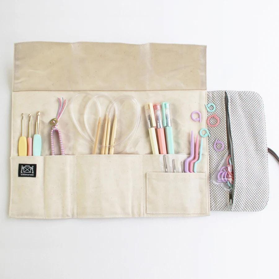 A beige pouch containing various knitting and crochet tools, including yarn, knitting needles, crochet hooks, and other accessories, neatly organized and ready for use.