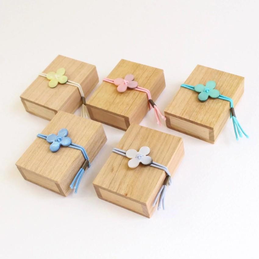 a collection of six wooden boxes with flower-shaped decorations, each with a tassel attached. The boxes are arranged in a row, with the first box on the left, the second box in the middle, the third box on the right, and the fourth box on the far right.