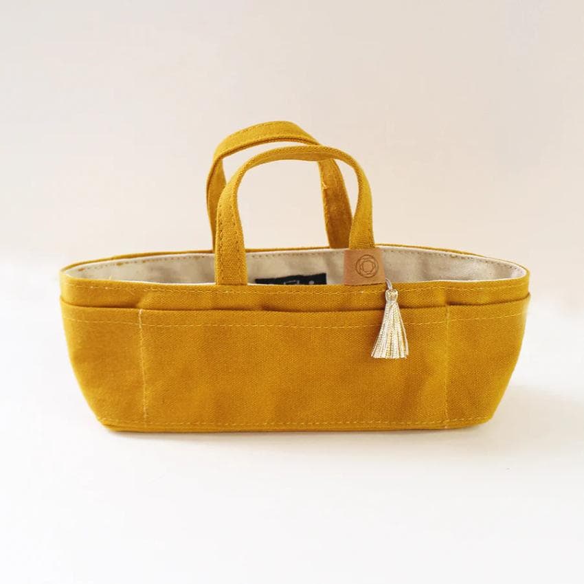 A yellow tote bag with a tassel hanging from the handle.