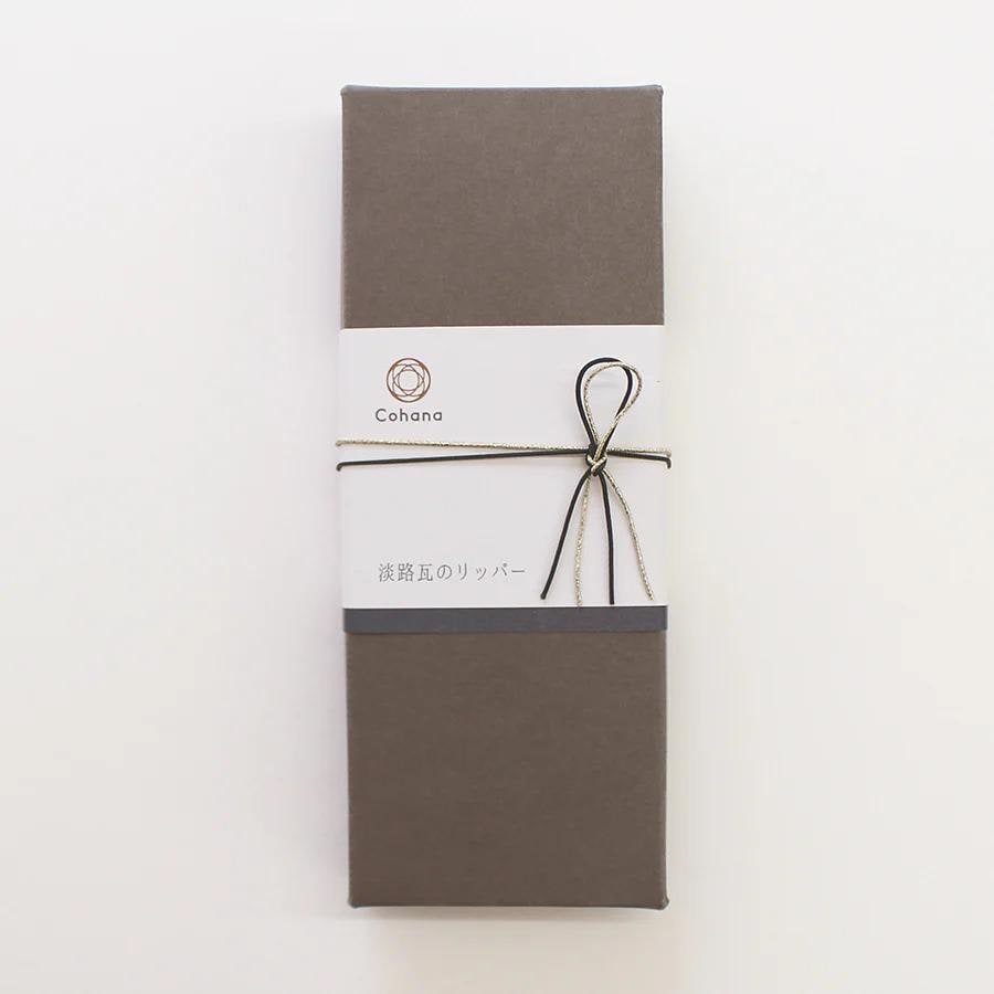 A brown box with a white label and a bow tied around it, placed against a white background.