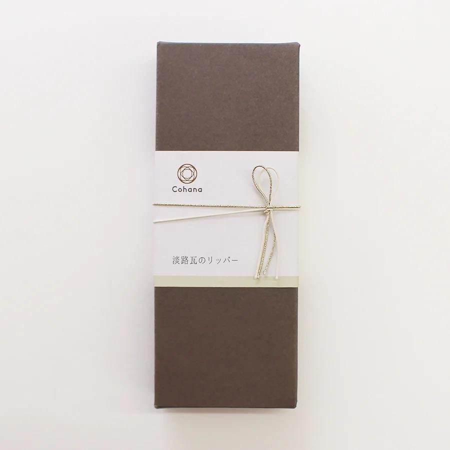 A brown box with a white label and a bow tied around it, placed against a white background.