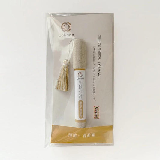 A package containing a small, cylindrical object with a tassel attached, which appears to be a product from the brand "Cohana".