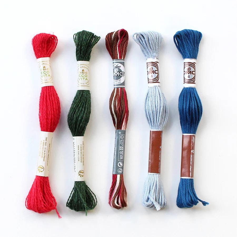 five spools of thread in various colors, including red, green, blue, and brown, arranged in a row.