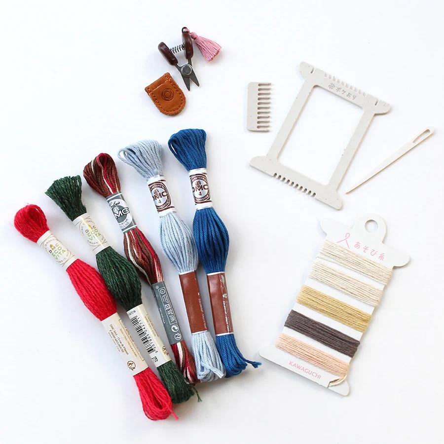 various sewing and crafting supplies, including spools of thread in different colors, a pair of scissors, a comb, and a wooden frame.