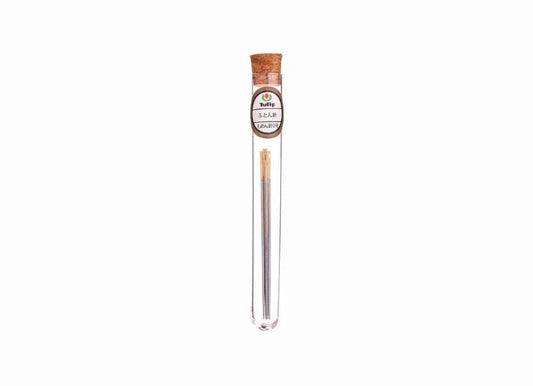 A clear glass tube containing a single object, which appears to be a small metal object, possibly a piece of jewelry or a decorative item.