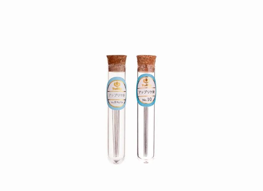 Two glass tubes with metal needles, each labeled with Japanese text.