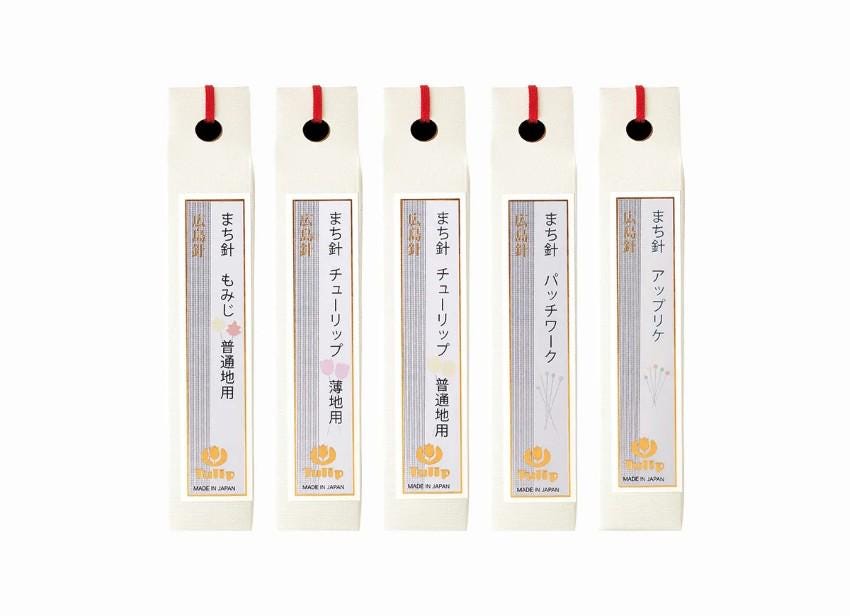 five identical white boxes with red handles, each containing Japanese text and a logo.