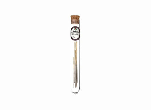 A clear glass tube containing a collection of gold crochet hooks.