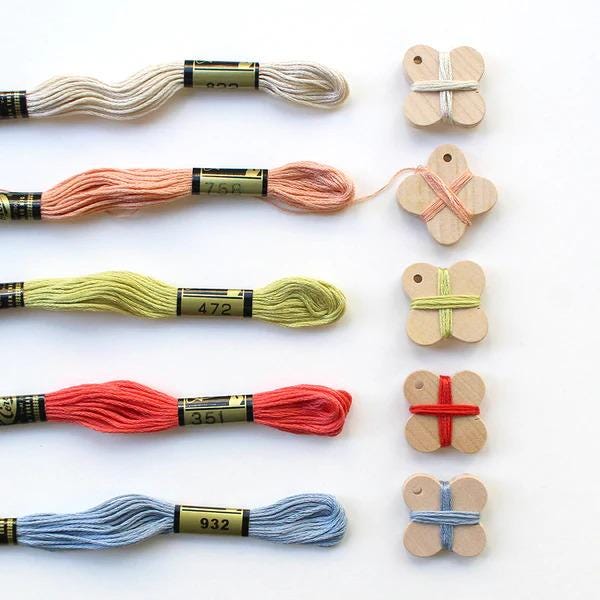 a collection of embroidery floss and wooden spool holders arranged on a white background.