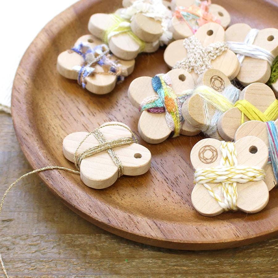 A wooden plate on a table holds various small wooden objects, including beads, strings, and other craft materials, arranged in a visually appealing manner.