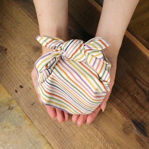 A pair of hands gently holding a colorful, striped cloth or fabric.