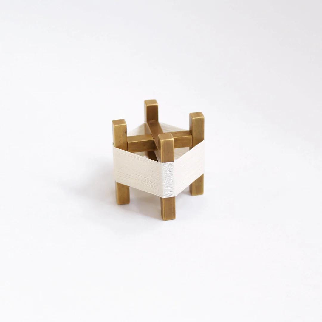 A small, metallic object with a white cloth wrapped around it, sitting on a plain white background.