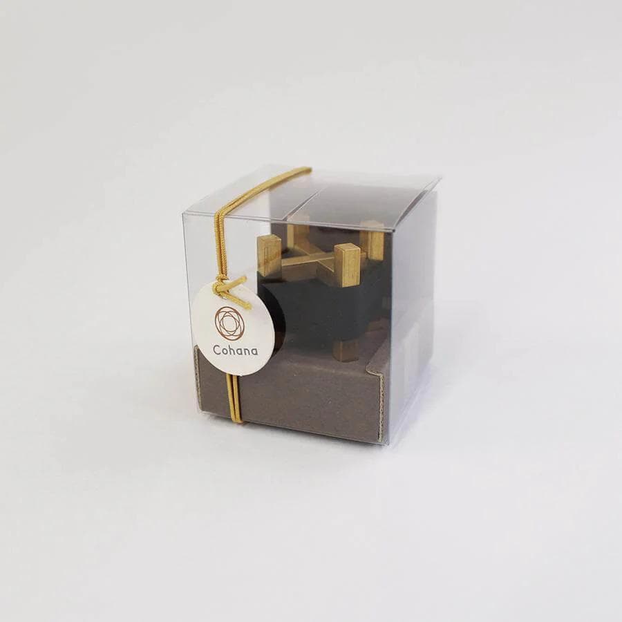 A clear plastic box with a gold ribbon and a white circular tag that says "Cohana".