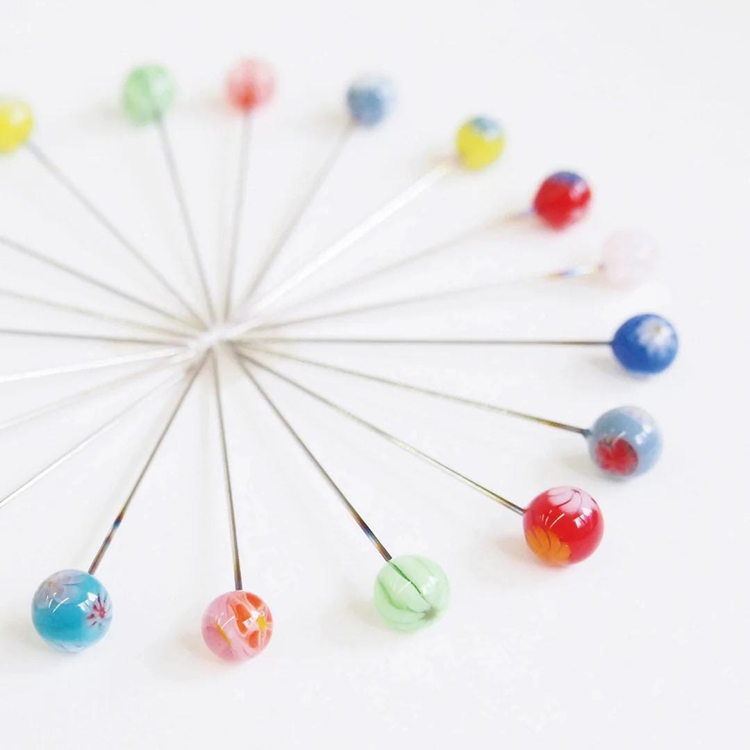 A collection of colorful glass beads arranged in a circular pattern on a white background.