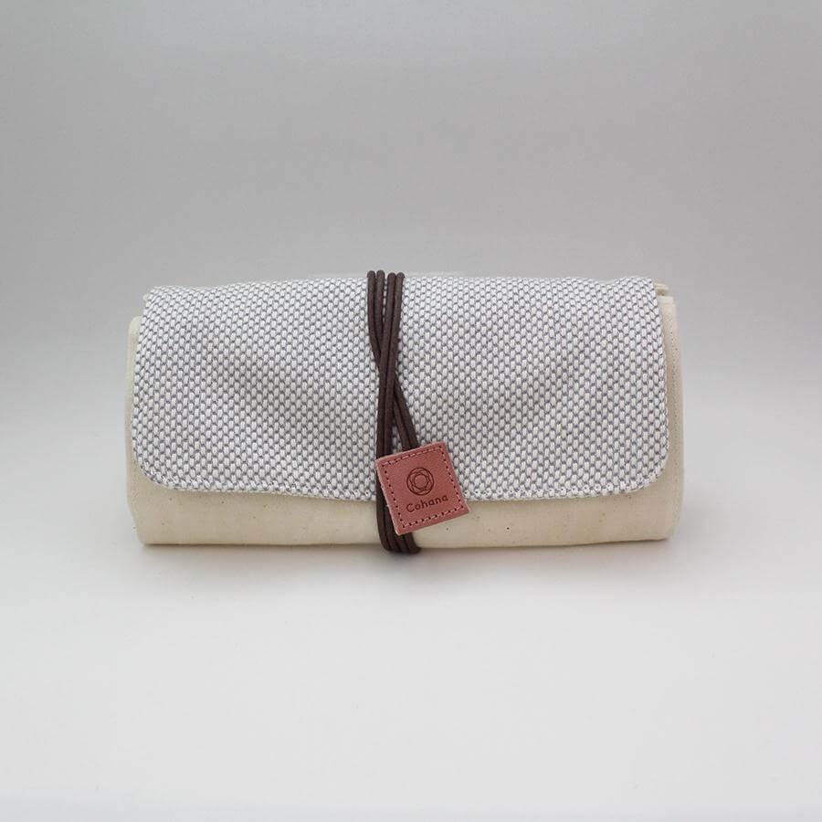 A beige cloth roll with a small red tag attached to it, sitting on a white surface.