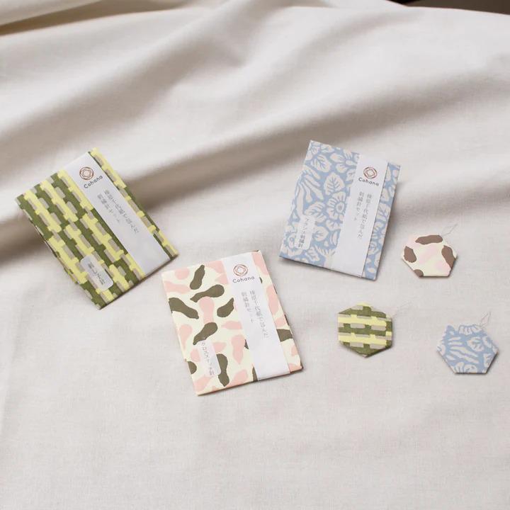 three different colored paper cards and some small hexagonal shapes on a white cloth.