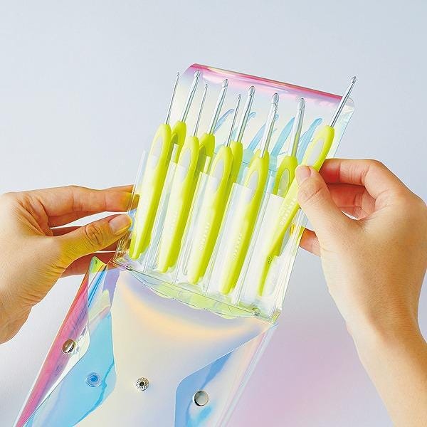A person's hands holding a transparent case containing a set of yellow crochet hooks.
