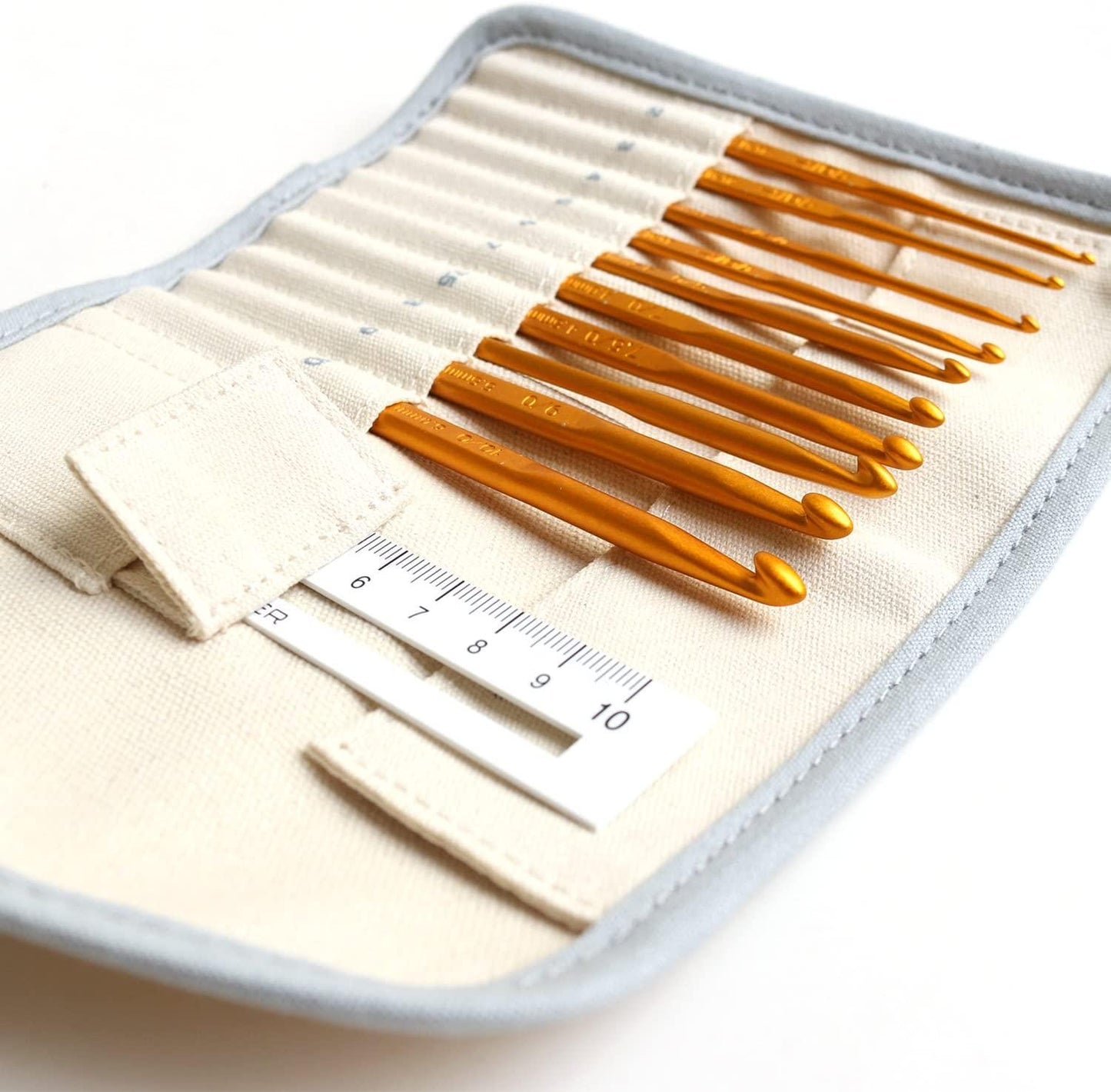 A crochet set with a ruler and a beige case, containing a total of nine crochet hooks.