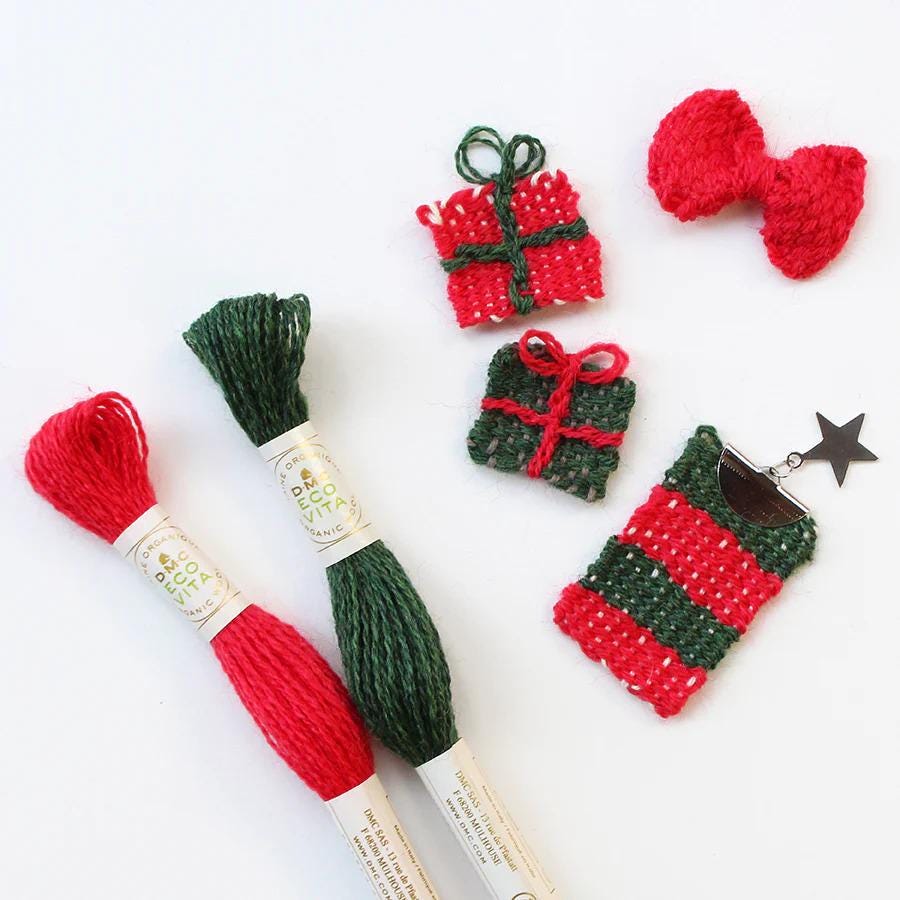 various knitted and crocheted items, including a red bow, a green and red gift box, and a red and green striped item, all placed on a white background.