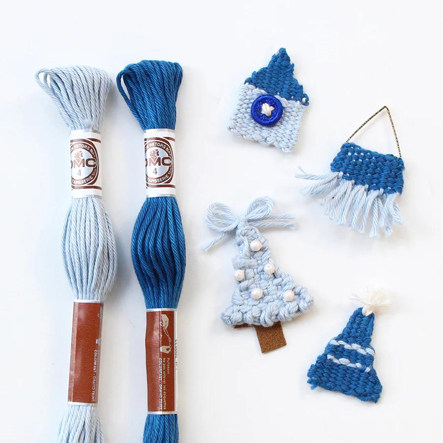 a variety of knitted and crocheted items, including a blue and white knitted hat, a blue and white crocheted tree, and a blue and white crocheted basket. The items are arranged on a white background, showcasing the craftsmanship and creativity involved in these handmade projects.