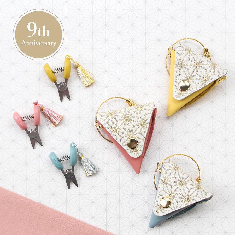 a collection of colorful and decorative scissors, tassels, and other accessories arranged on a patterned background.