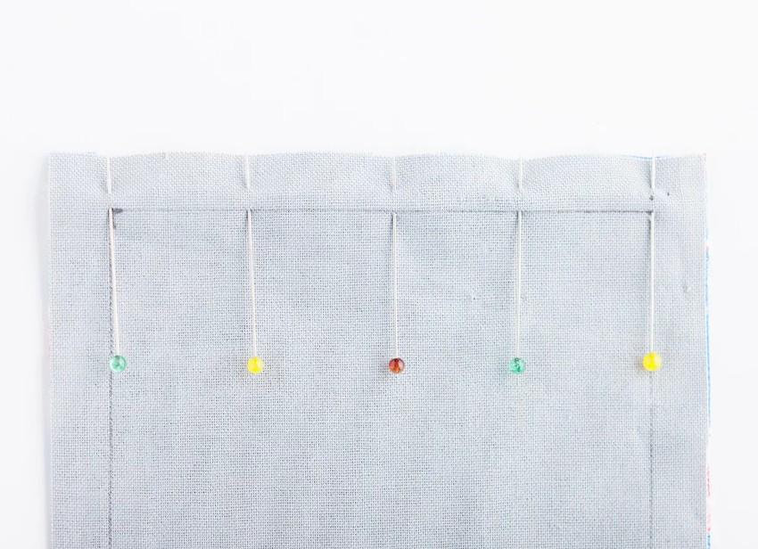 a close-up view of a gray fabric with five colorful push pins attached to it, arranged in a row.