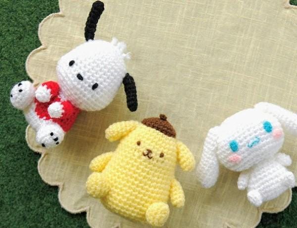 Crocheted stuffed animals, including a white dog, a yellow dog, and a white rabbit, arranged on a scalloped edge.