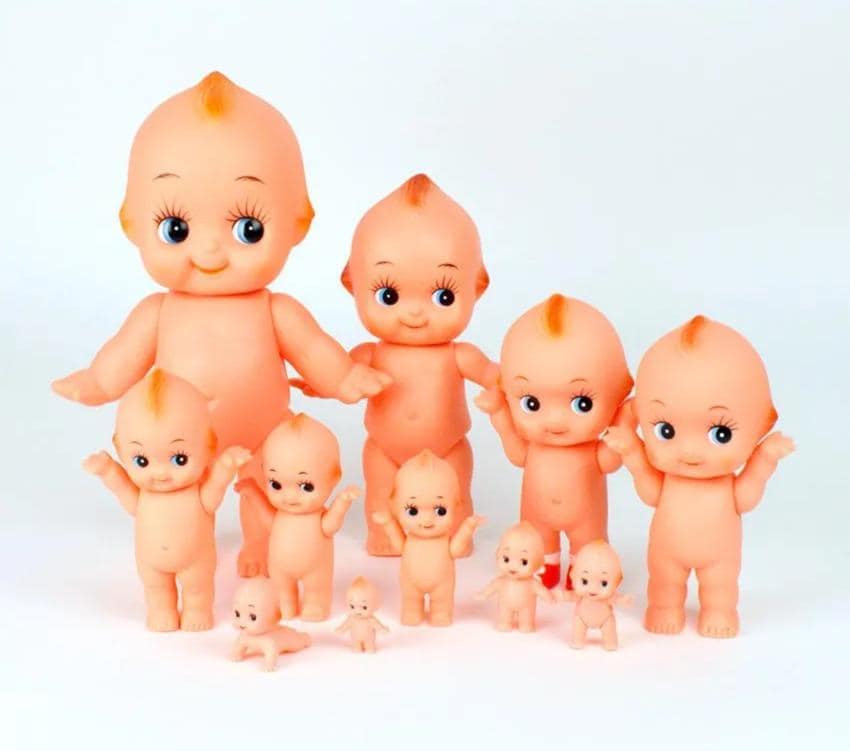 A group of small, orange-colored baby dolls or figurines arranged together against a white background.