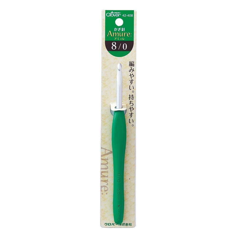 A green crochet hook with a white handle, designed for Amure crochet.