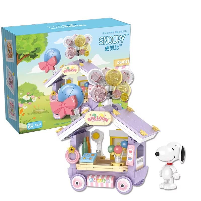 A toy vending machine with a Snoopy figurine standing next to it, and a box of the toy is visible in the background.