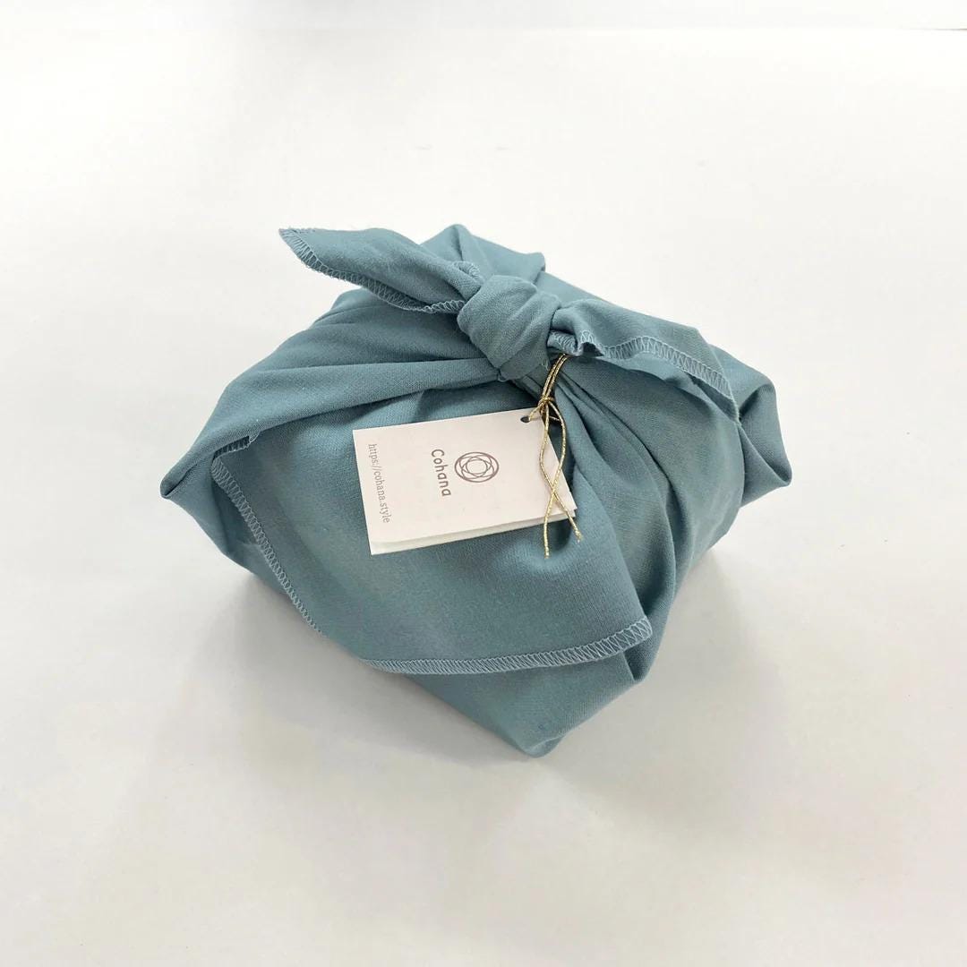 A wrapped package with a tag attached, sitting on a white surface.
