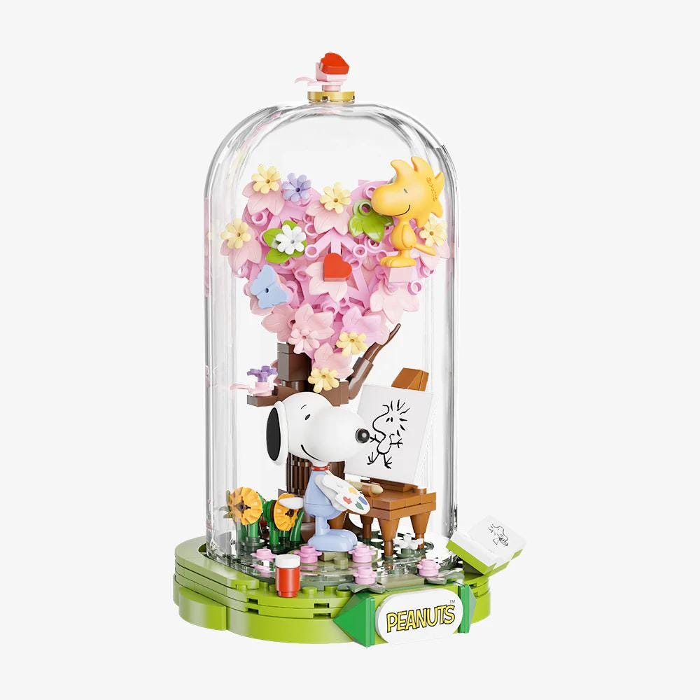 A Peanuts-themed diorama featuring a Peanuts character sitting in a chair, surrounded by flowers and other Peanuts-related elements.