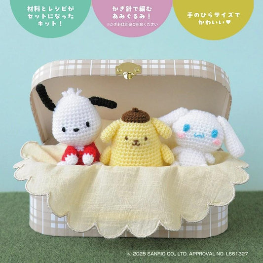A crocheted stuffed animal set, including a white dog, a yellow dog, and a white rabbit, sitting together in a decorative box.