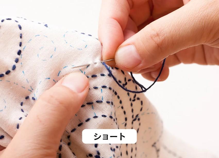 A person's hands are shown carefully stitching a piece of fabric with a needle and thread, with the text "おおそう" visible in the image.