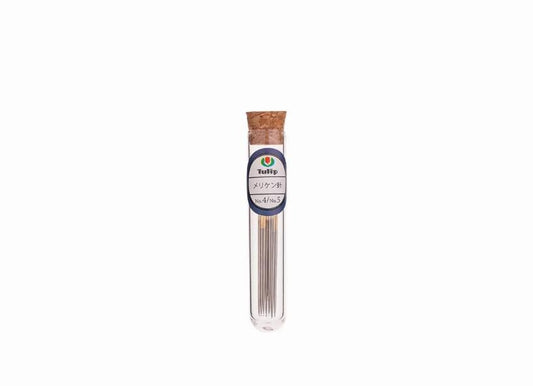 A clear glass tube containing a collection of metal needles, with a cork stopper at the top.