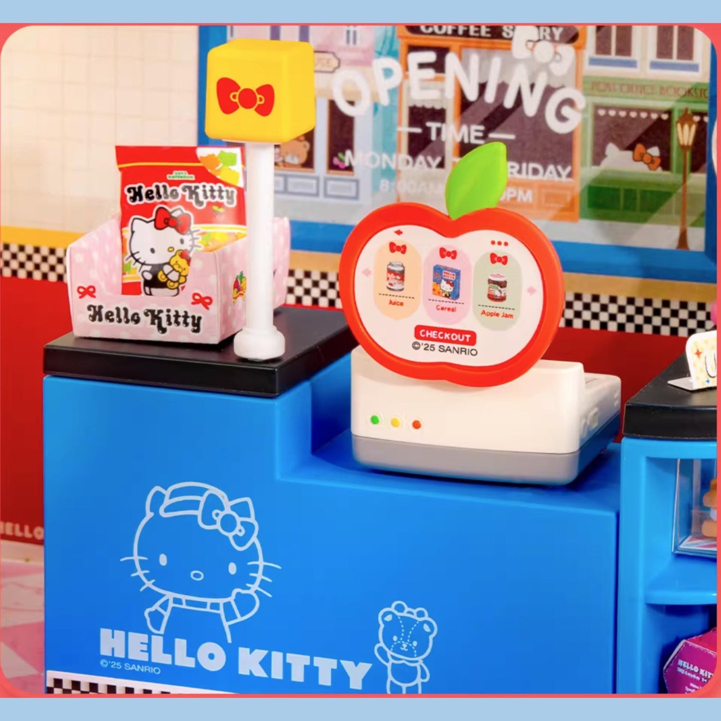 A Hello Kitty-themed toy cash register with a checkout screen and a toy apple with a bow on top, along with a Hello Kitty toy.