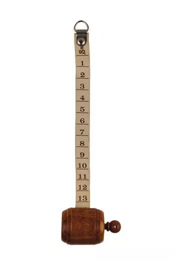 A wooden barrel with a metal ring attached to it, displaying a series of numbers on a beige ribbon.