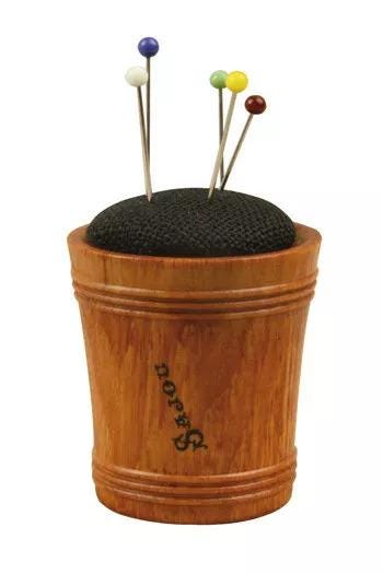 A wooden cup with a black pinking shear pin holder on top, containing colorful pins.