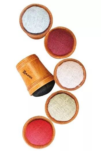 a collection of six small wooden containers, each containing a different colored fabric, arranged in a circular pattern.