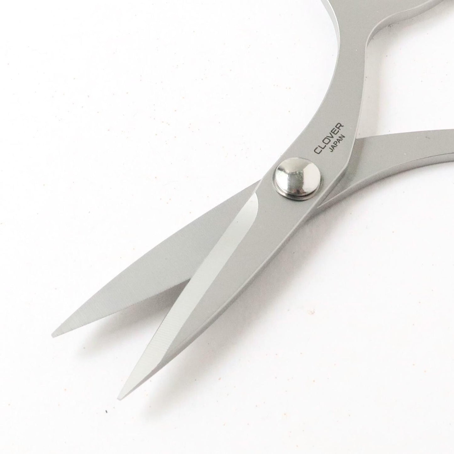 A pair of silver scissors with the brand name "CLOVER" printed on the blades.