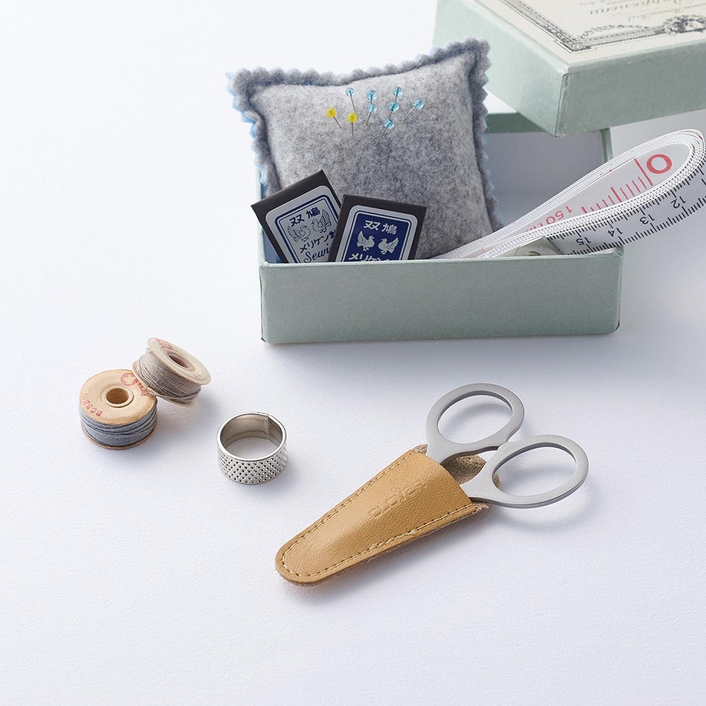 A collection of sewing and crafting supplies, including a pair of scissors, a measuring tape, and a small box with various sewing items inside.