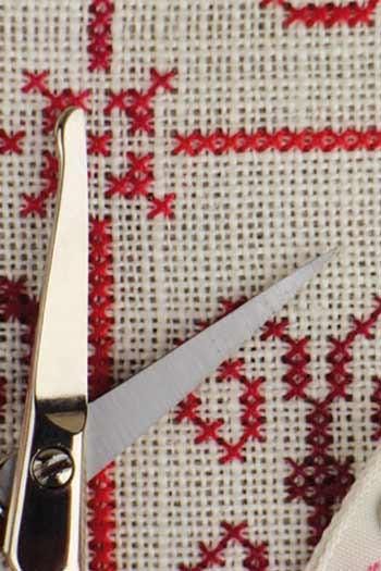A pair of scissors with red embroidery on a white background.