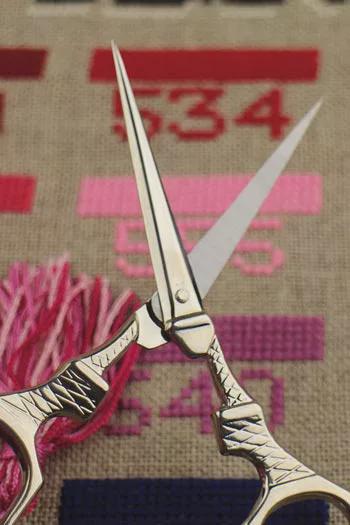 A pair of silver scissors with a pink tassel is prominently displayed against a background with the number 534.