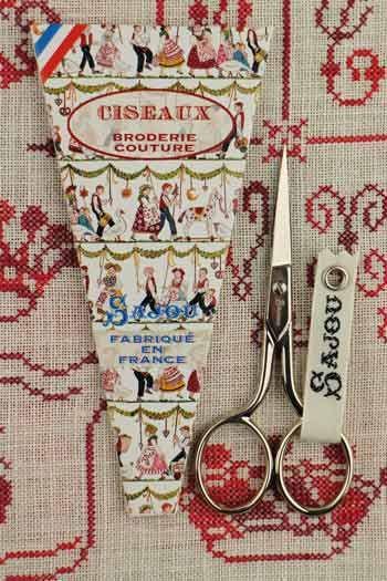 a pair of scissors and a package of fabric scissors, both placed on a patterned fabric background.