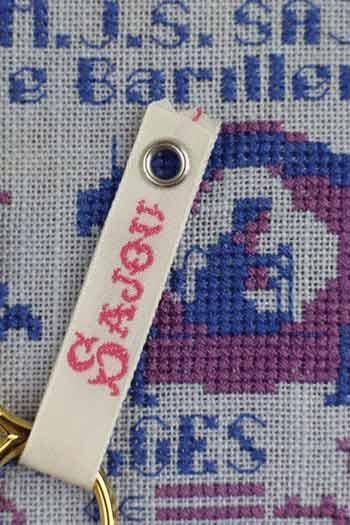 a cross-stitch pattern with a keychain attached to it.