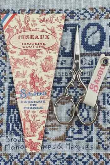 a pair of scissors and a piece of paper with text and illustrations, all placed on a patterned background.